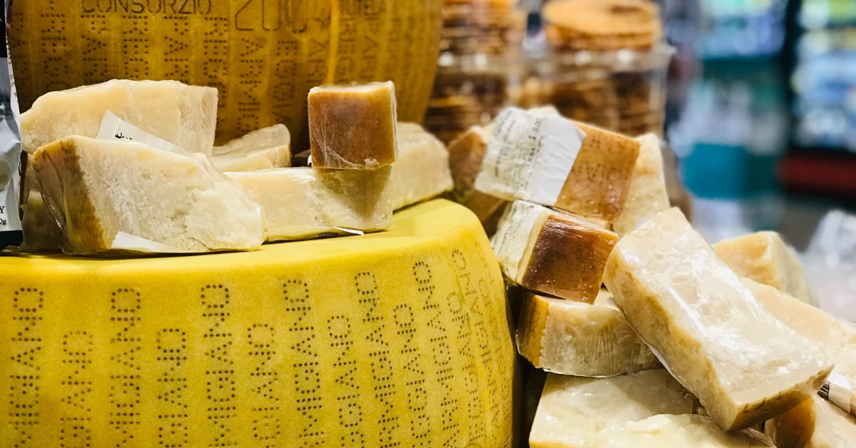 Parmigiano Reggiano cheese wheels and wedges, with markings visible on the rind.